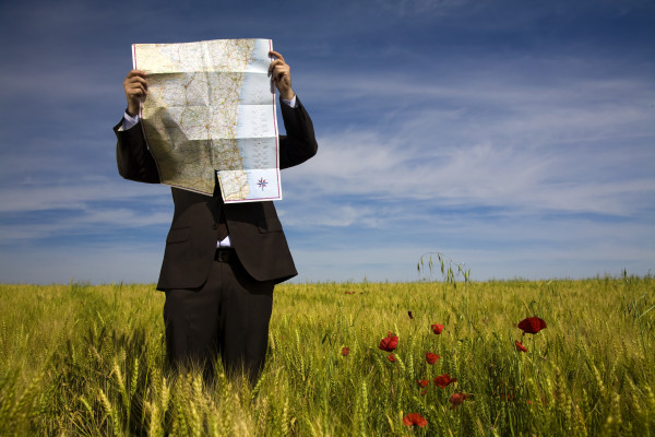 Businessman-lost-in-field-using-a-map